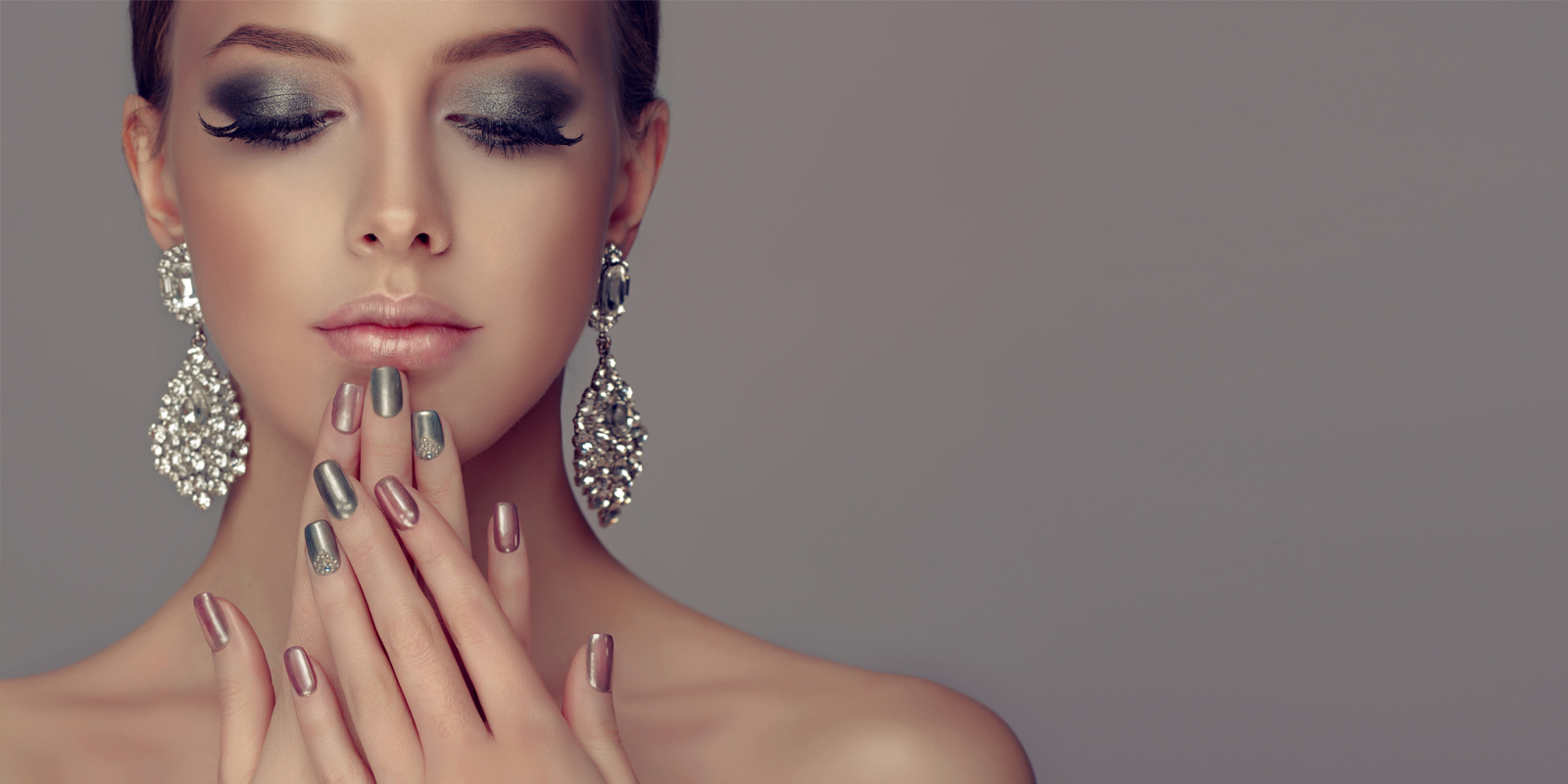 Close-up of a woman with elegant makeup and large silver earrings.