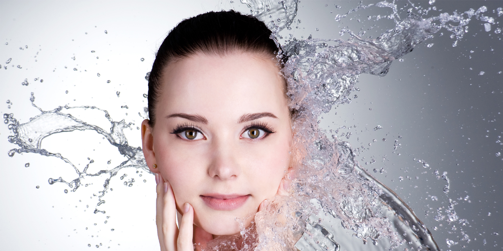 Close-up of a woman with water splashing on one side of her face.