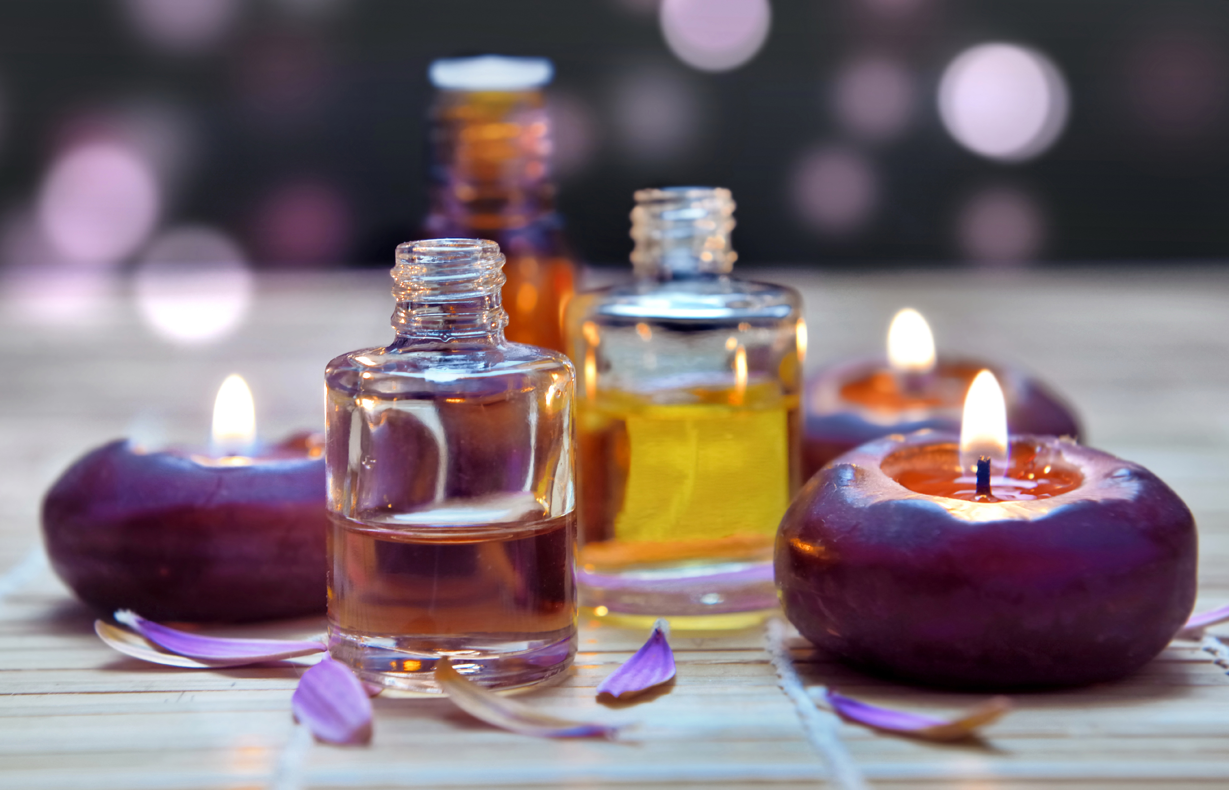 Glass bottles with essential oils and lit candles creating a relaxing ambiance. Glass bottles with essential oils and lit candles creating a relaxing ambiance.
